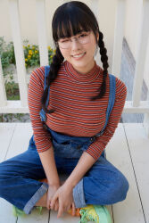 1girl black_hair braid breasts crossed_legs glasses_on_head gravure_idol japanese_(nationality) large_breasts looking_at_viewer medium_hair multicolored_sweater on_floor one_eye_closed outdoors overalls photo_(medium) shinonome_umi smile solo sweater twin_braids wink