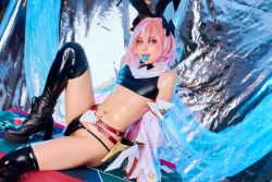 1boy absurdres astolfo_(fate) astolfo_(fate)_(cosplay) black_ribbon boots bulge cosplay fate/grand_order fate_(series) hair_ribbon highres latex latex_boots latex_legwear latex_panties latex_thighhigh_boots latex_thong latex_top looking_at_viewer male_focus mouth_hold panties photo_(medium) pink_hair poker_chip purple_eyes ribbon shiny_skin solo testicle_peek trap underwear velvetchann