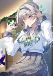 1girl absurdres black_hairband black_ribbon blush bow bowtie cellphone closed_mouth collared_shirt firefly_(honkai:_star_rail) firefly_(spring_missive)_(honkai:_star_rail) gradient_eyes green_bow green_bowtie green_pupils grey_hair grey_sailor_collar grey_skirt hair_between_eyes hair_intakes hair_ornament hairband hand_in_own_hair heart highres holding holding_phone honkai:_star_rail honkai_(series) long_sleeves memeiradesuyo multicolored_eyes phone plaid_bow plaid_bowtie plaid_clothes pleated_skirt ribbon sailor_collar selfie shirt skirt smartphone smile solo two-tone_eyes white_shirt white_sleeves