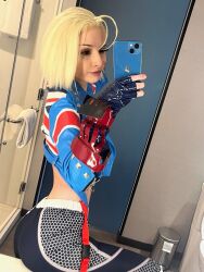 Rule 34 | 1girl, ass, black gloves, black leggings, blonde hair, blue jacket, cammy white, cammy white (cosplay), capcom, cellphone, cosplay photo, cropped jacket, female focus, fingerless gloves, gauntlets, gloves, highres, holding, holding phone, jacket, leggings, open clothes, open jacket, phone, photo (medium), real life, runabayo, selfie, short hair, smartphone, solo, street fighter, street fighter 6, union jack, union jack print