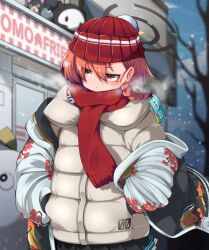 1girl blue_archive blurry blurry_background blush braid coat datemegane earrings hair_between_eyes halo hands_in_pockets jewelry mole mole_under_eye neru_(blue_archive) outdoors red_hair red_scarf scarf snowing solo white_coat winter winter_clothes