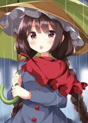 1girl blurry blurry_background blush braid brown_eyes brown_hair brown_hat capelet commentary dress grey_dress hat highres holding holding_umbrella long_hair long_sleeves open_mouth rain red_capelet ruu_(tksymkw) solo touhou twin_braids umbrella yatadera_narumi