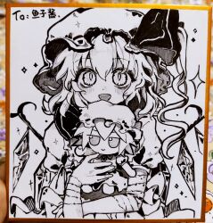 1girl bandaged_arm bandages blush character_doll commentary_request crystal crystal_wings doll flandre_scarlet fumo_(doll) greyscale hat highres holding holding_doll looking_at_viewer mob_cap monochrome one_side_up open_mouth photo_(medium) puffy_short_sleeves puffy_sleeves remilia_scarlet shikishi short_sleeves slit_pupils smile solo touhou traditional_media wings youshouhaoxianzhe