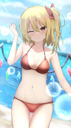 1girl ;) absurdres beach bikini blonde_hair blush bow breasts commentary_request crystal day dutch_angle flandre_scarlet hair_bow hand_up head_tilt highres medium_hair mountainous_horizon one_eye_closed one_side_up outdoors red_bikini red_bow small_breasts smile solo swimsuit szl touhou wings