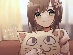 1girl blurry blurry_background brown_hair cat-shaped_pillow closed_mouth commentary dated fang flower green_eyes hair_flower hair_ornament highres holding holding_pillow idolmaster idolmaster_cinderella_girls indoors jacket long_sleeves looking_at_viewer maekawa_miku nnnn paw_print paw_print_pattern pillow pink_flower pink_jacket print_jacket short_hair sitting smile solo twitter_username upper_body