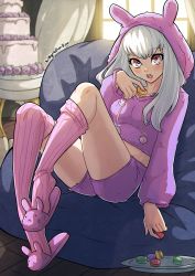 1girl alternate_costume artist_name breasts cake fire_emblem fire_emblem:_three_houses food highres hood hoodie kinkymation light_blush long_hair looking_at_viewer lysithea_von_ordelia macaron nintendo open_mouth pink_eyes shorts sitting slippers small_breasts solo sweets white_hair window