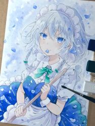 1girl apron art_tools_in_frame blue_eyes blue_petals bow braid closed_mouth green_bow grey_hair hair_bow highres holding izayoi_sakuya looking_at_viewer maid maid_headdress petal_in_mouth photo_(medium) puffy_short_sleeves puffy_sleeves short_sleeves smile solo touhou traditional_media twin_braids waist_apron white_apron wrist_cuffs yuzugoori